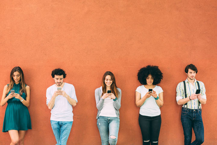 Group of people on their phones against a wall