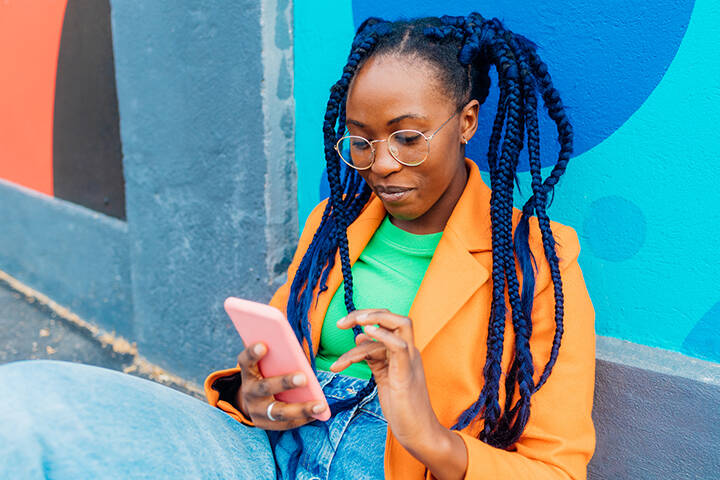 Woman holding phone against a colourful wall